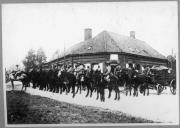 Grupo de militares a cavalo junto a edifício.