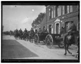 Militares a cavalo e veículo de tracção animal junto a edifício.