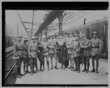 Grupo de militares e civil em gare dos caminhos-de-ferro.