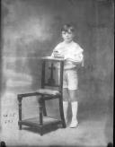 Uma criança civil junto a uma cadeira.