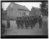 Militares a caminharem em formatura junto a edifícios militares.