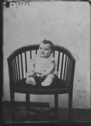 Criança sentada numa cadeira.