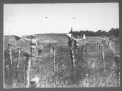 Três militares junto a campo armadilhado com arame farpado.