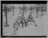 Três militares junto a cemitério.