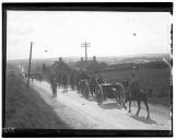 Militares a cavalo e veículo de tracção animal na estrada.