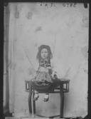 Uma criança com traje tradicional minhoto, sentada em cima da mesa.
