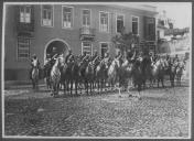 Grupo de militares a cavalo junto a edidício.