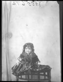 Criança civil com traje tradicional minhoto, sentada em cima da mesa.