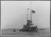 Vista frontal do navio com a bandeira hasteada.